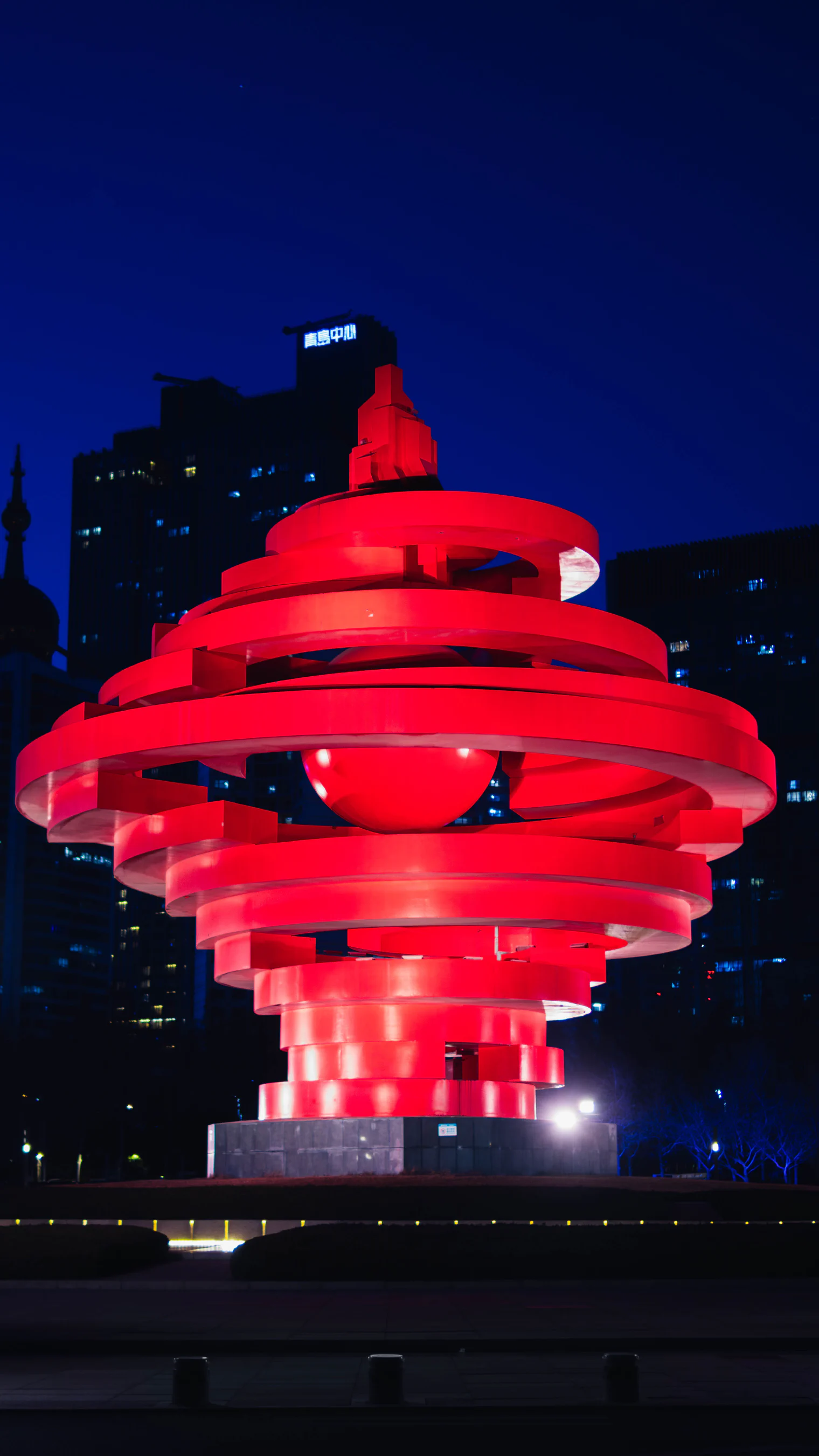 深蓝夜空下，亮着红色灯光的五月的风雕塑。